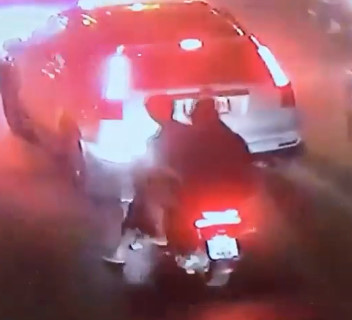 Couple on Scooter Sandwiched Between Cars